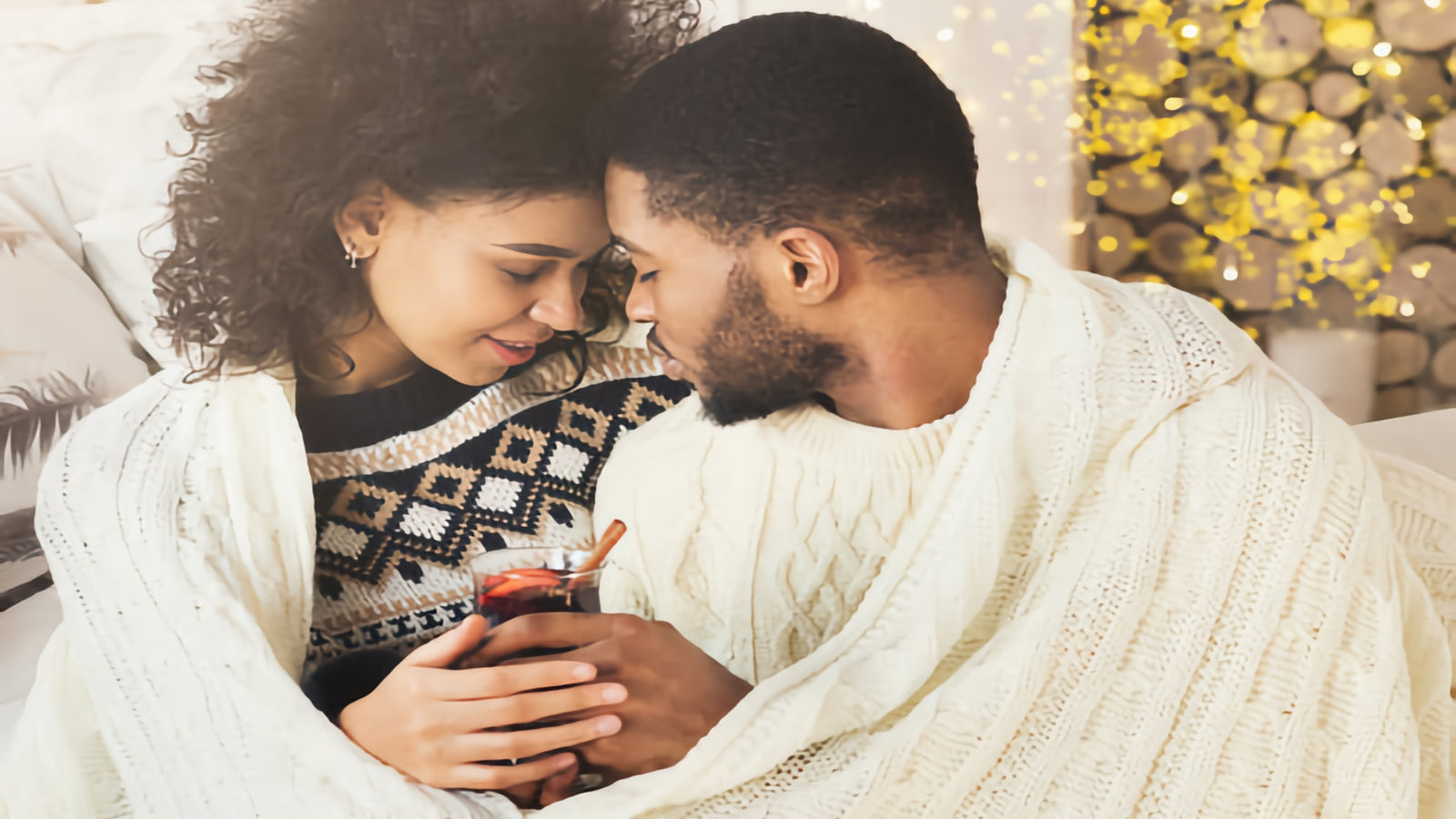 A woman and man about to kiss and both wrapped in a blanket