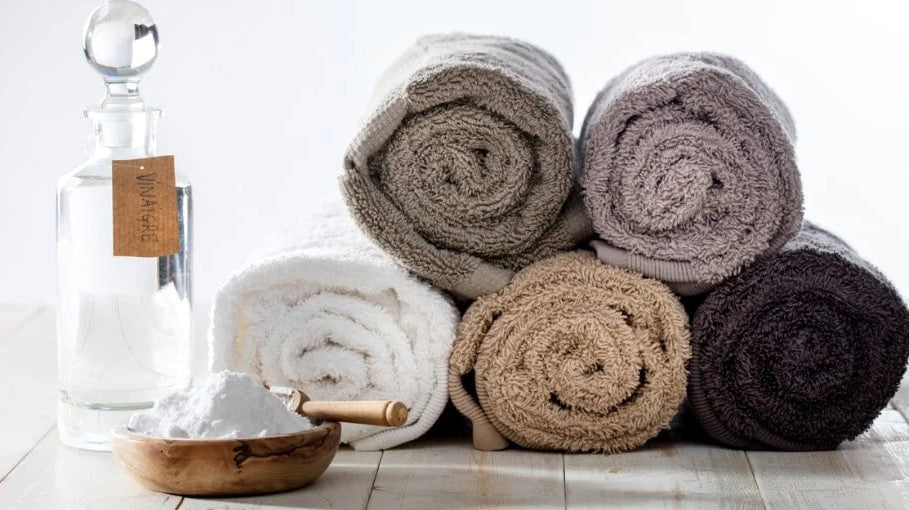How to "Break In" Your Bath Towels: All About Your New Towels' Break-In Period Stacked Rolled Multi Color Towels Fine Linens with Glass Bottle and Solution