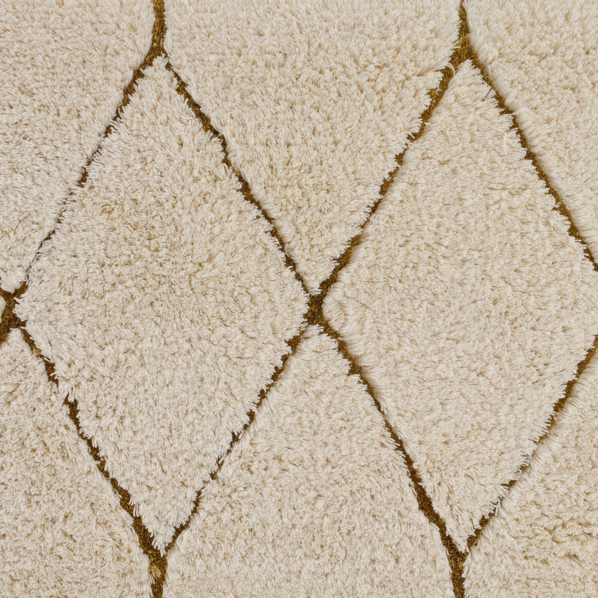 Gold Abyss Habidecor Heritage Bath Rug beside a bath tub