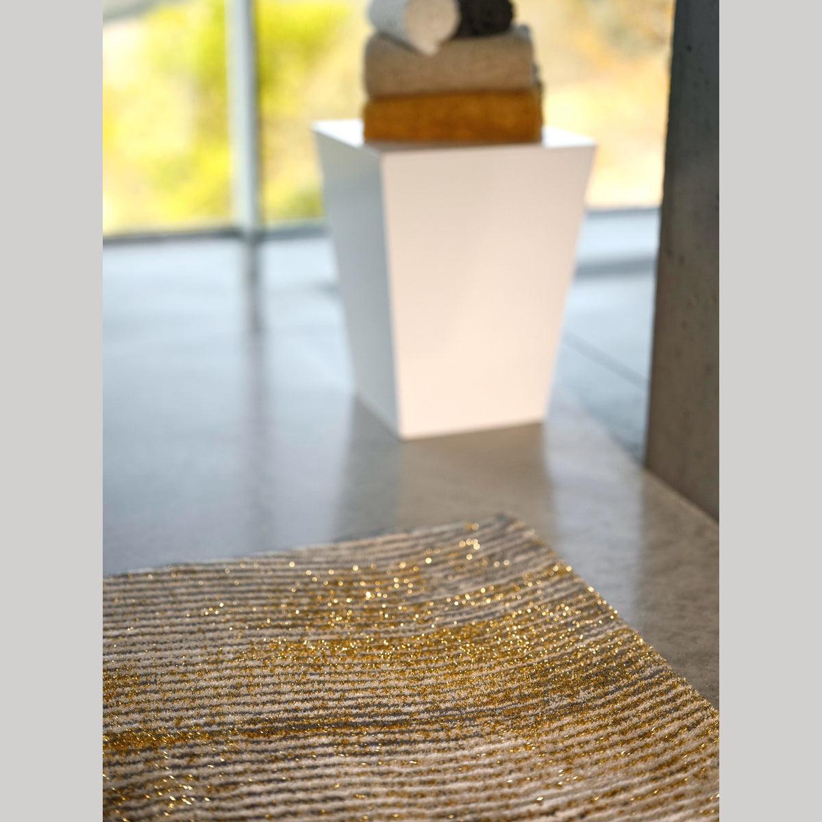 Abyss Habidecor Lana Bath Rug in Gold (800) on cement floor