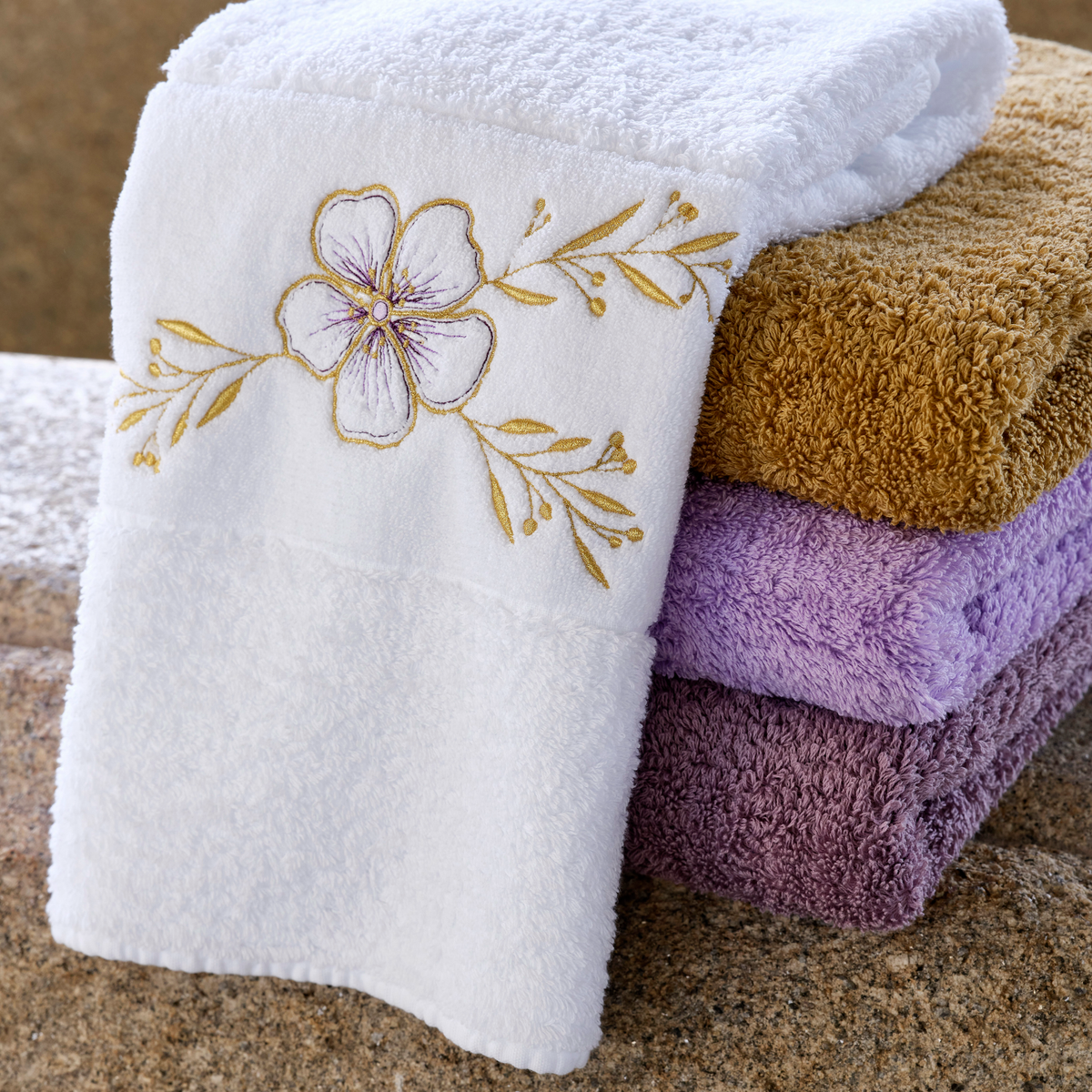 Abyss Heloise Embroidered Bath Towels in Gold (108) color stacked with folded luxury towels