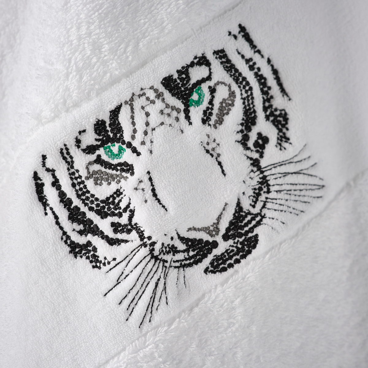 Close-up of an Abyss Tiger Towel, a luxury towel crafted in Egyptian Giza Cotton with a black and green tiger face design.