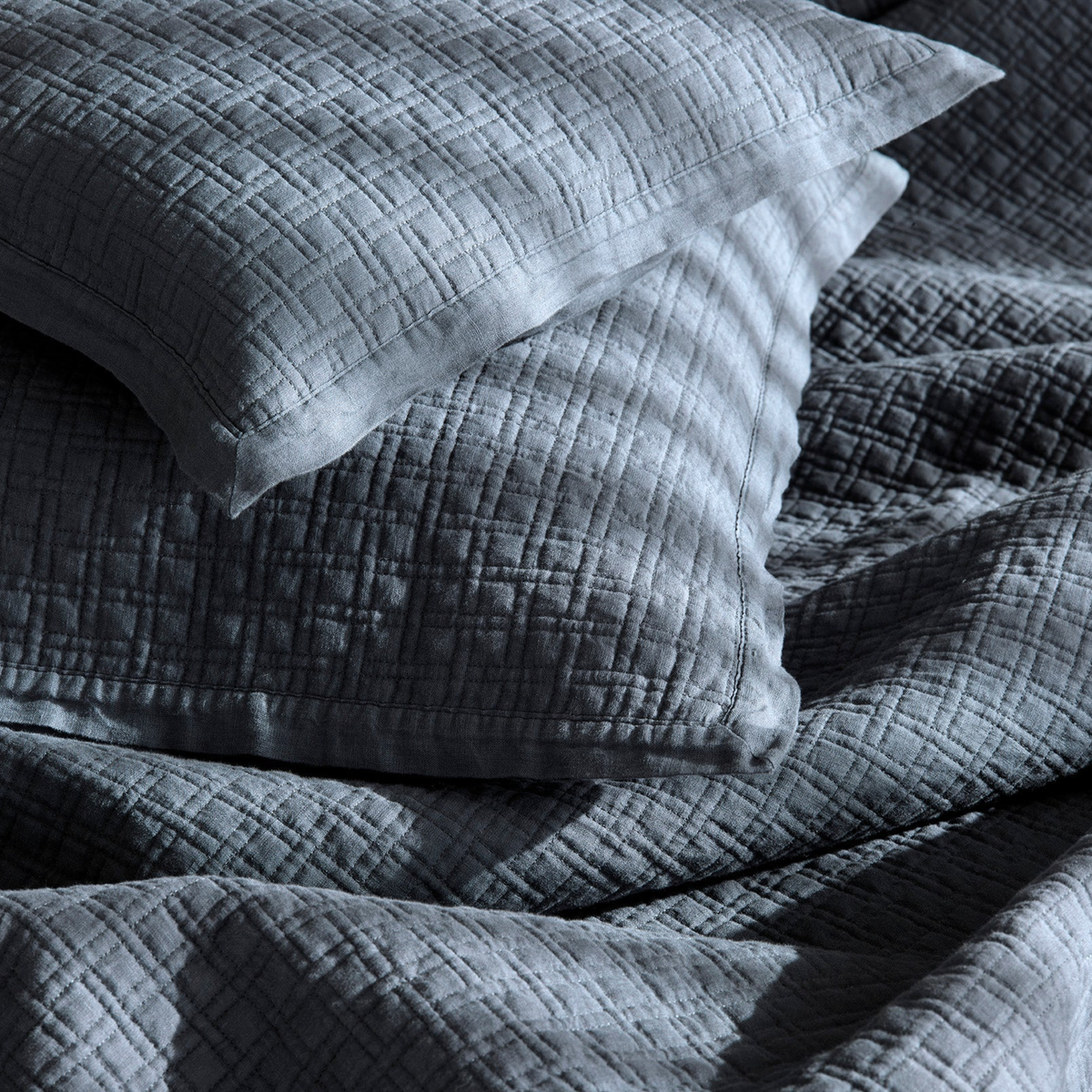 Two Loch Blue Amalia Adorno Quilted Pillows resting on a matching bedding bedspread