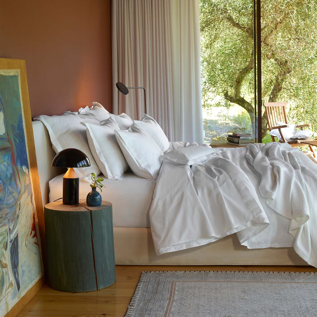 A bed with white Giza 94 Egyptian Cotton percale Amalia Fresco Bedding, next to a wooden bedside table