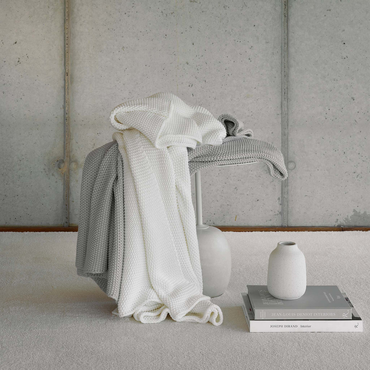 Amalia Lilium Throws in Cool Grey and Natural colors draped on a table