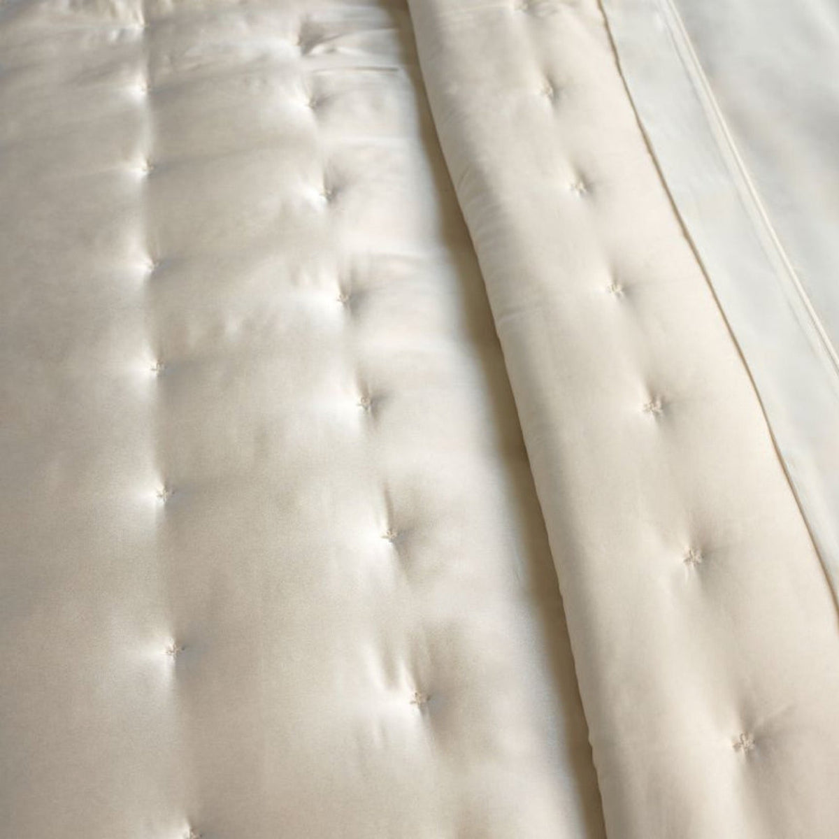 Off-white mulberry silk sateen quilted bedding with a folded edge.