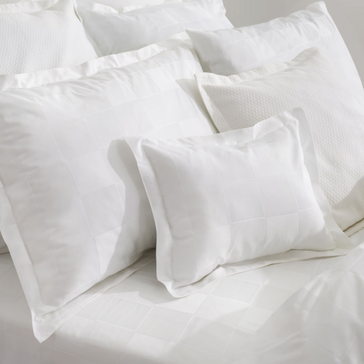 A collection of white Amalia Sagres Giza 92 Jacquard shams and pillows