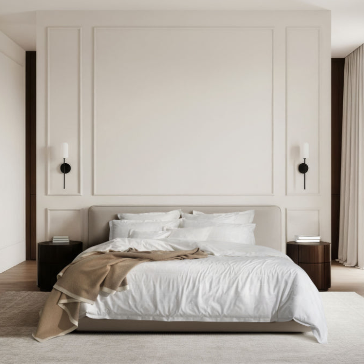 A bed with White Amalia Sagres Giza 92 Jacquard Bedding and a tan throw between two wood nightstands against a paneled wall with two sconces.