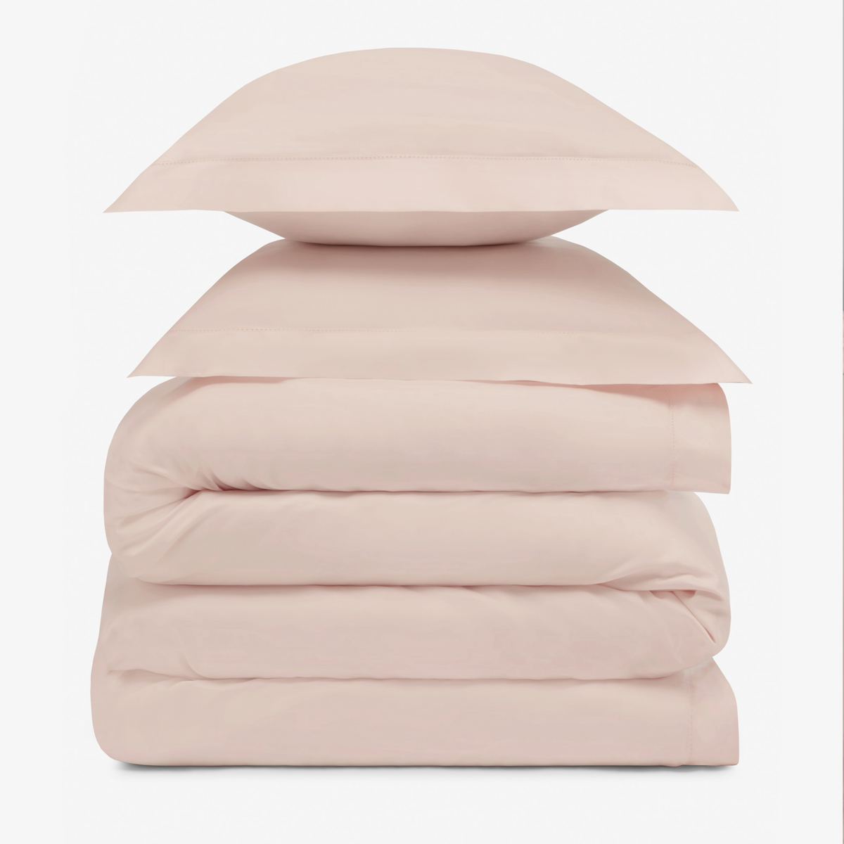 A stack of two Charm Pink pillows resting on folded Amalia Duvet Bedding Sheets
