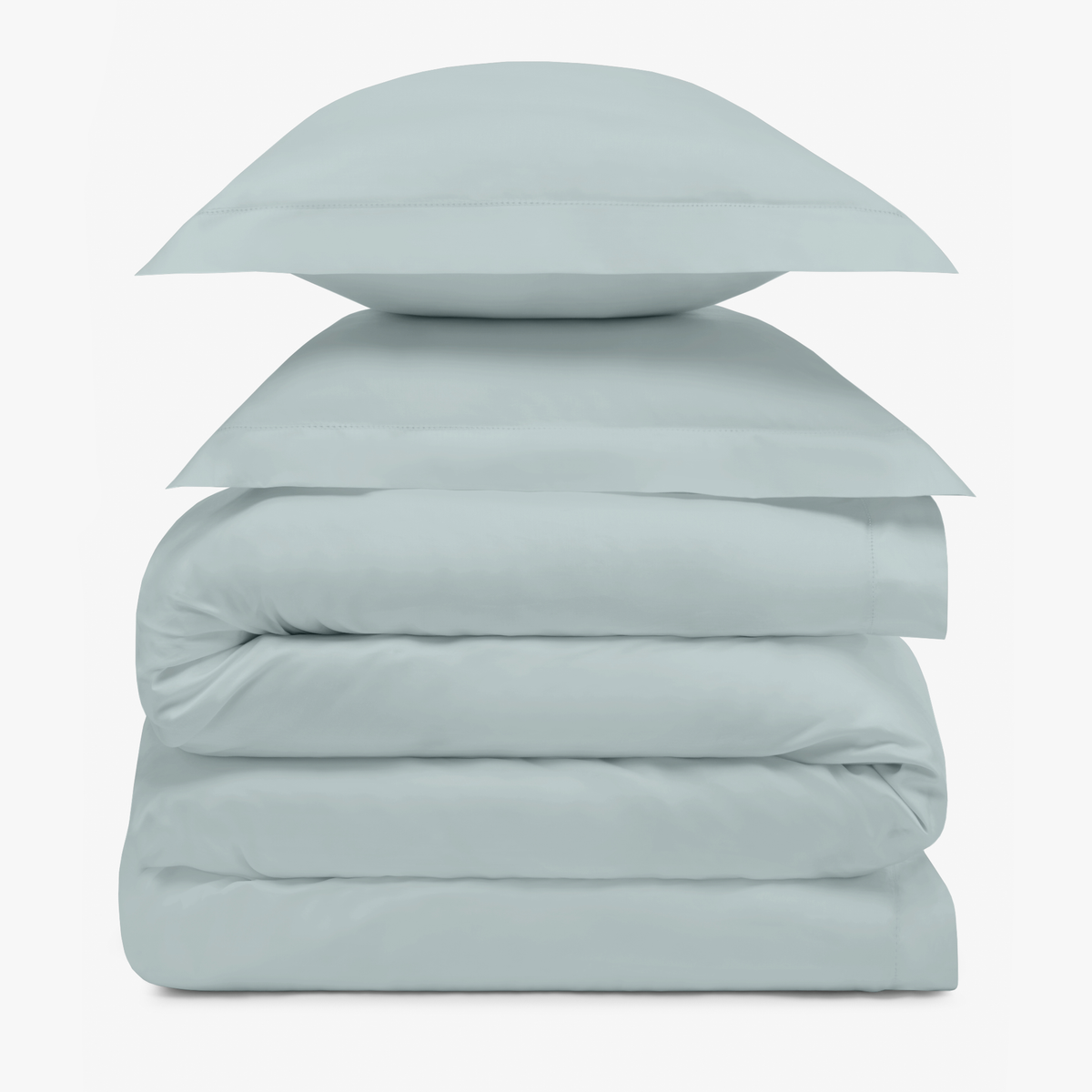 A stack of two Mist Blue pillows resting on folded Amalia Duvet Bedding Sheets