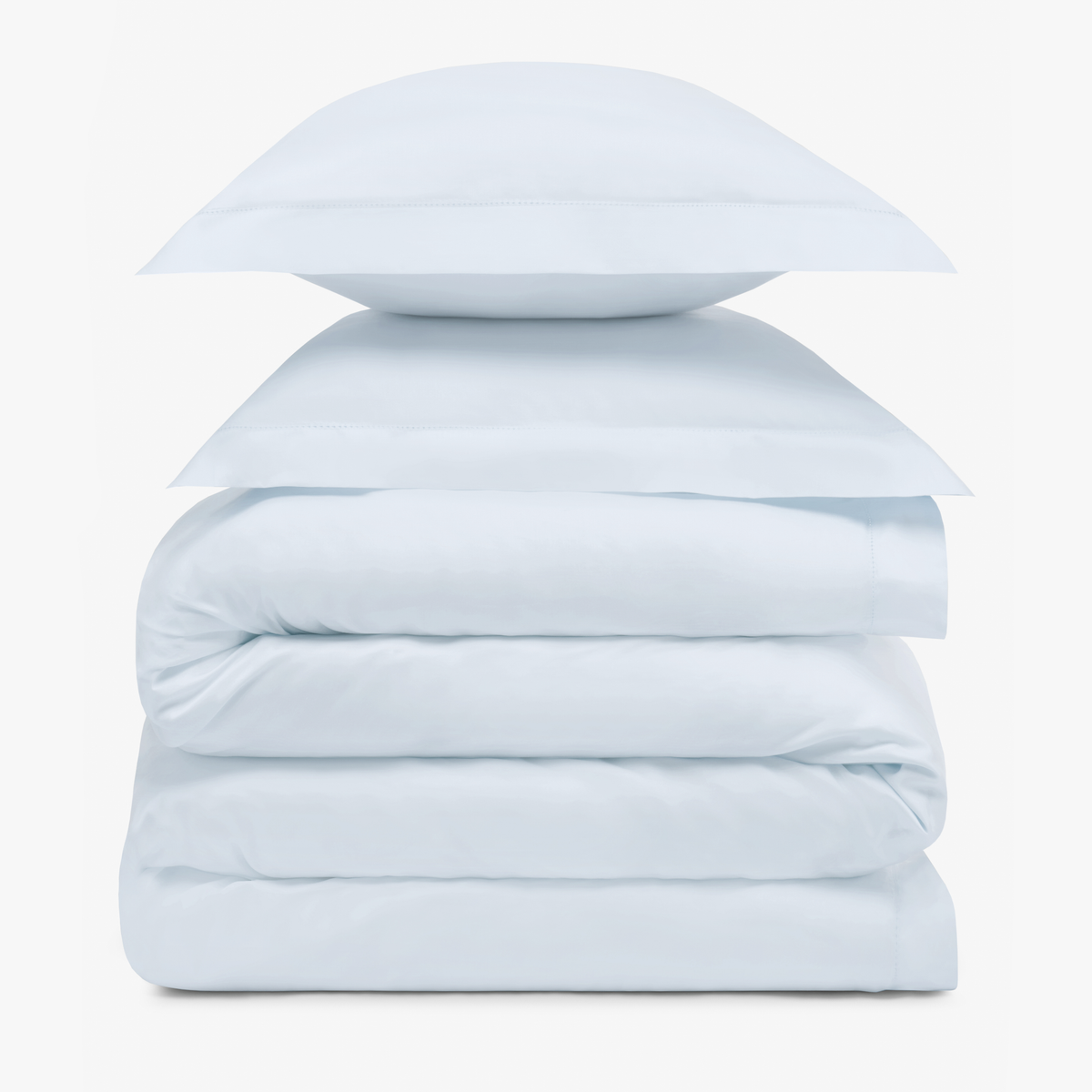 A stack of two Pale Blue pillows resting on folded Amalia Duvet Bedding Sheets