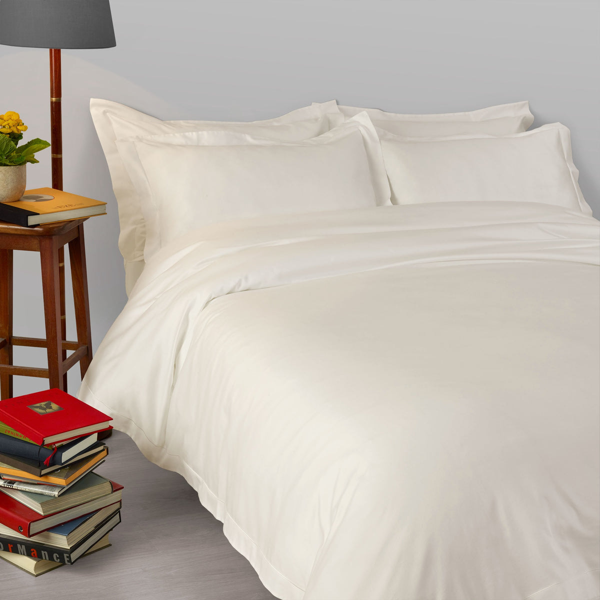 A bed made with 430 thread count White Amalia Suave Giza 94 Bedding, next to a lamp