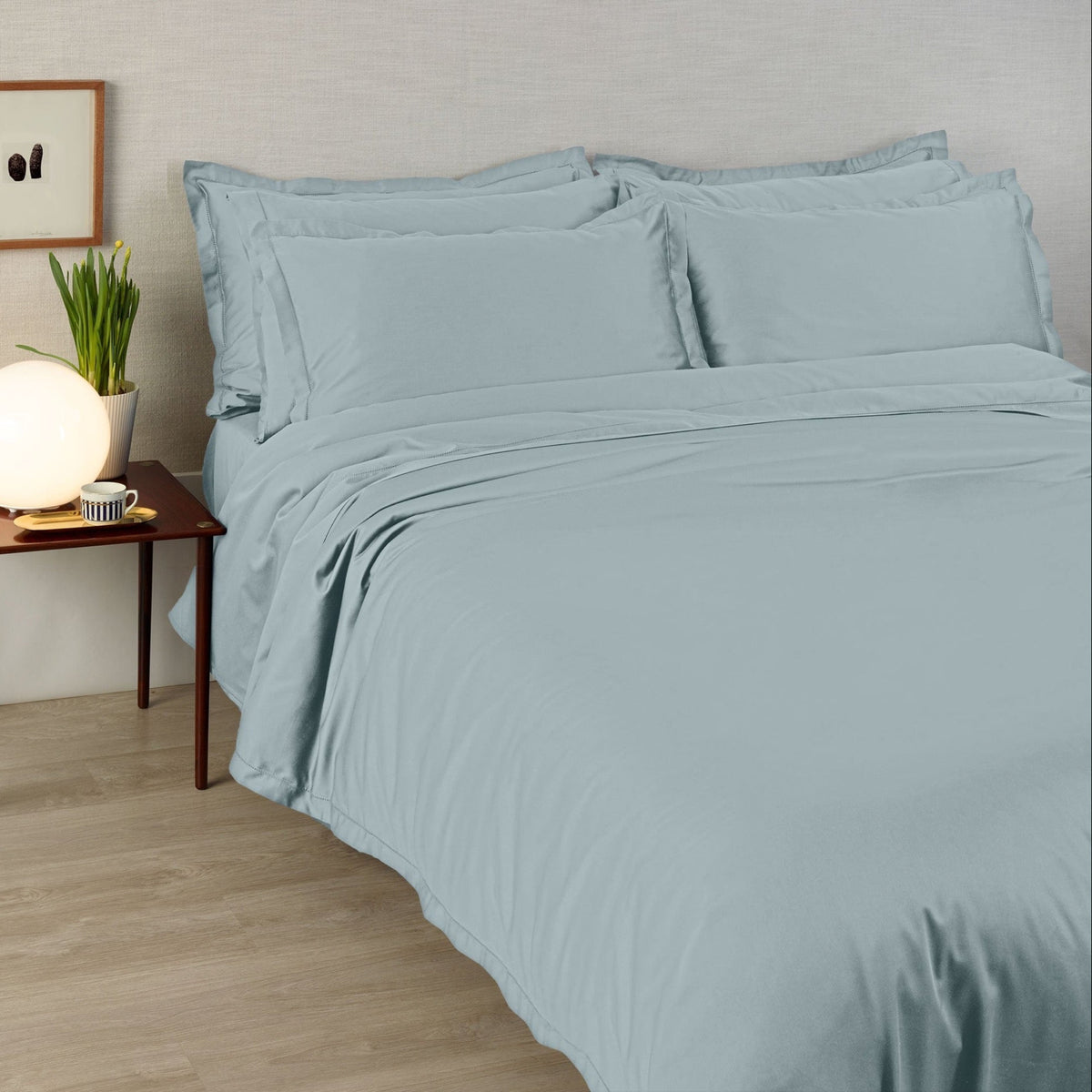 A bed made with 430 thread count Mist Blue Amalia Suave Giza 94 Bedding, next to a lamp