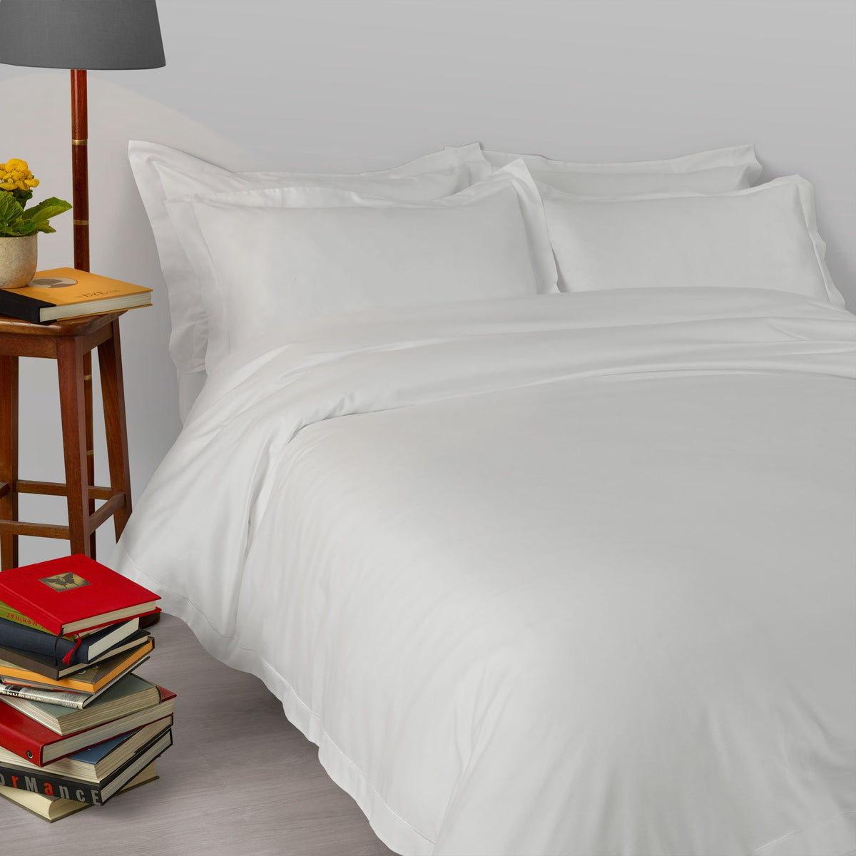 A bed made with 430 thread count Pale Grey Amalia Suave Giza 94 Bedding, next to a lamp
