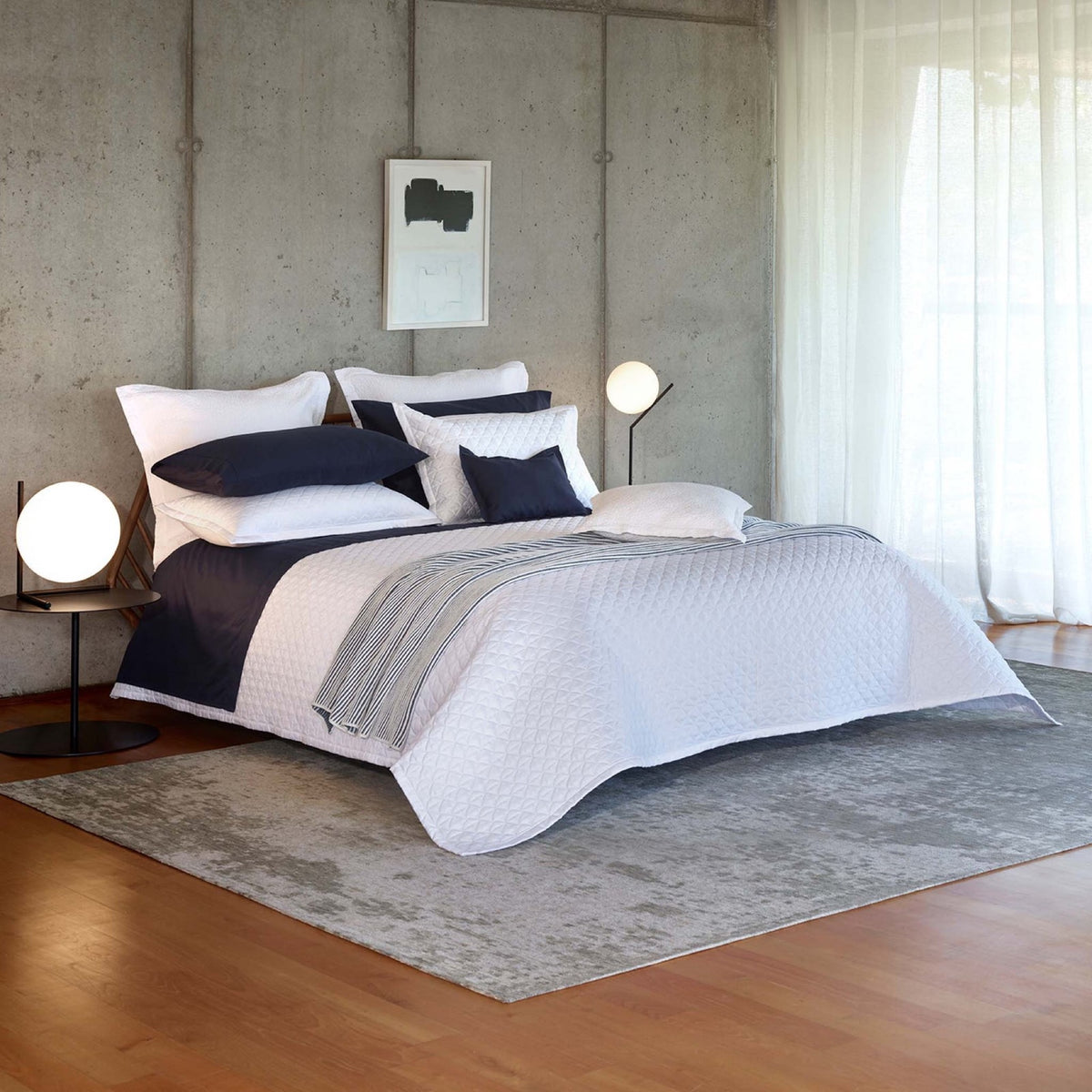 A bed in a well lit room with White Amalia Suave Quilted Bedding