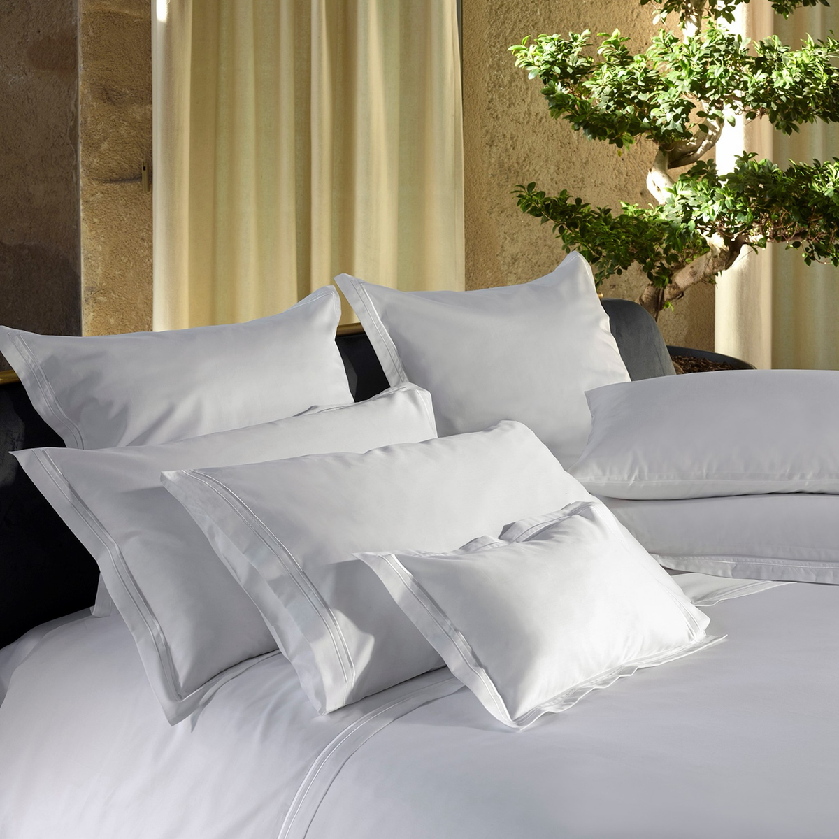 A bed with a White Amalia Sublime Giza 45 Cotton duvet and several stacked pillows