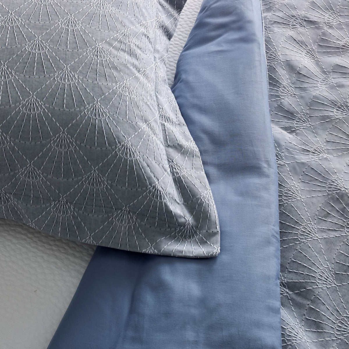 Closeup of Indigo-colored Ann Gish Crest Duvet Set and its blue reverse side