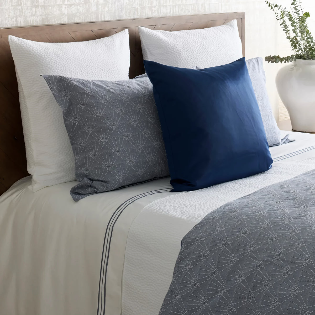 Side view of Indigo-colored Ann Gish Crest Duvet Set With blue pillow