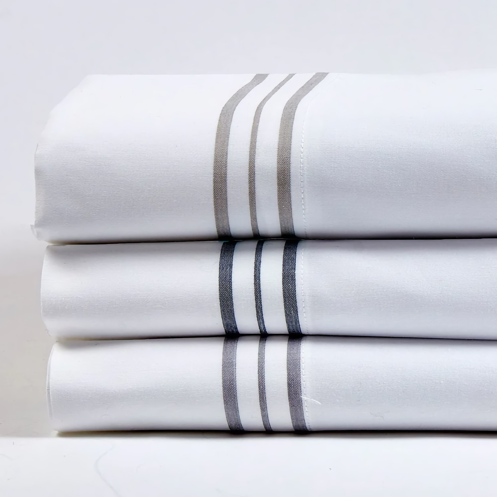 Stack of Ann Gish Hem Stripe Bedding in All Colors
