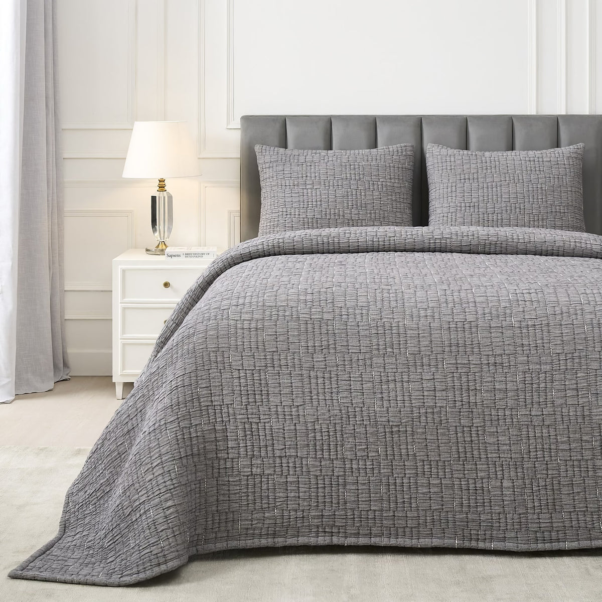 A neatly made bed with a Charcoal colored Ann Gish Pickstitch Coverlet Set in a modern bedroom