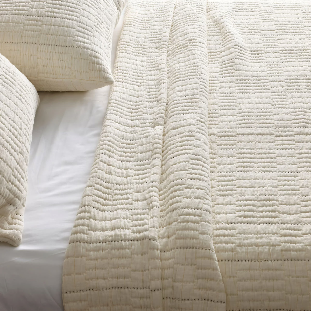 Close-up of a neatly made bed with Bone colored Ann Gish Pickstitch Coverlet Set