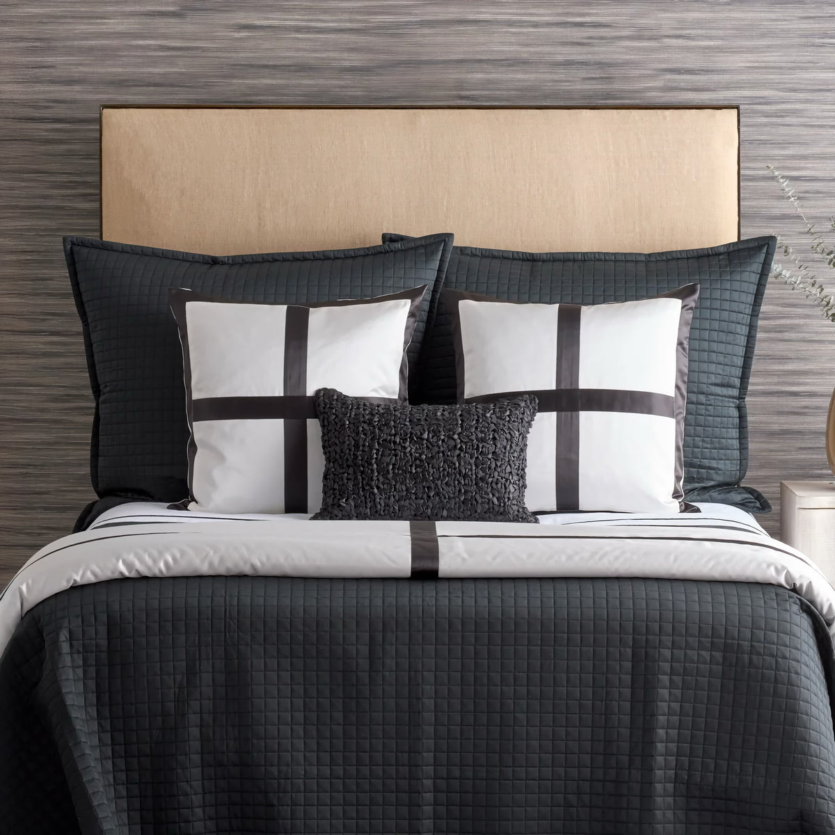 A neatly made bed with lyocell bedding, black and white pillows, and a textured gray accent pillow.