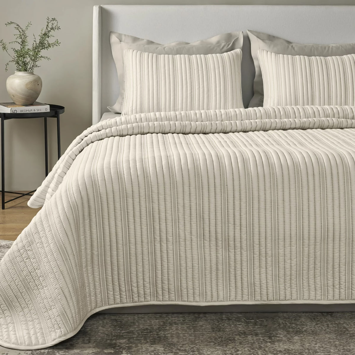 A neatly made bed with a Bone colored Ann Gish Rib Coverlet Set