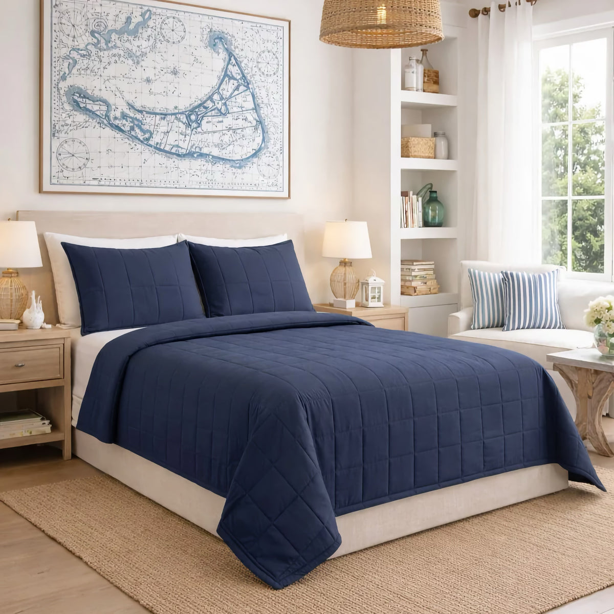 A bedroom with a Marine colored Ann Gish Slub Tencel Quilted Coverlet Set, two nightstands, lamps, and a map artwork above the headboard