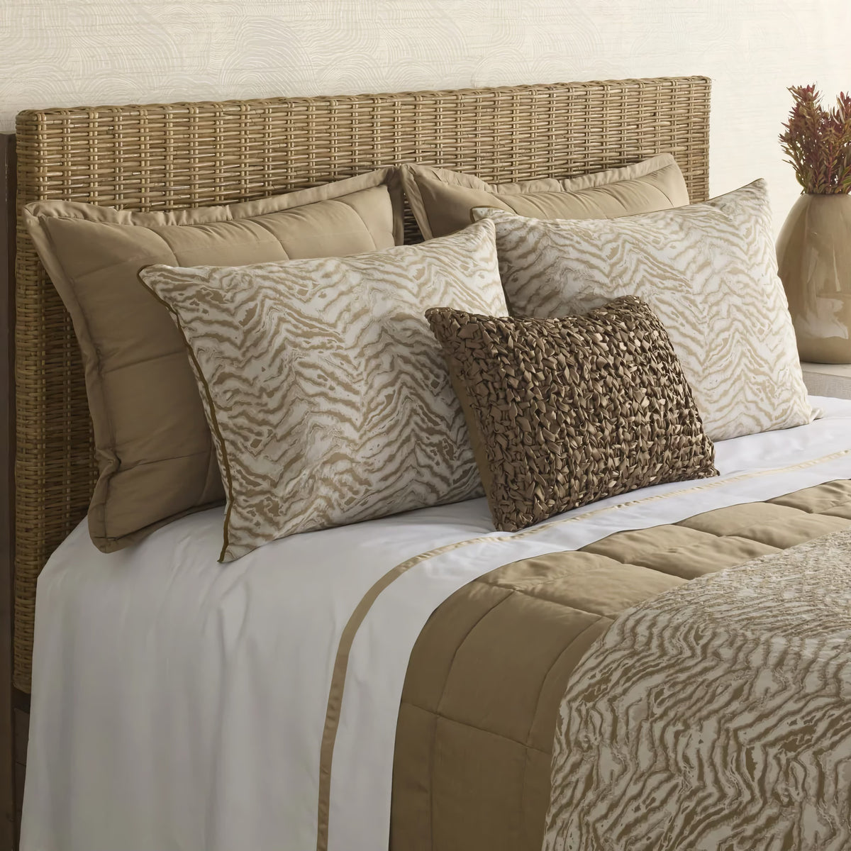 A bed with a wicker headboard, animal print pillows, and a Cafe au Lait colored Ann Gish Slub Tencel Quilted Coverlet Set