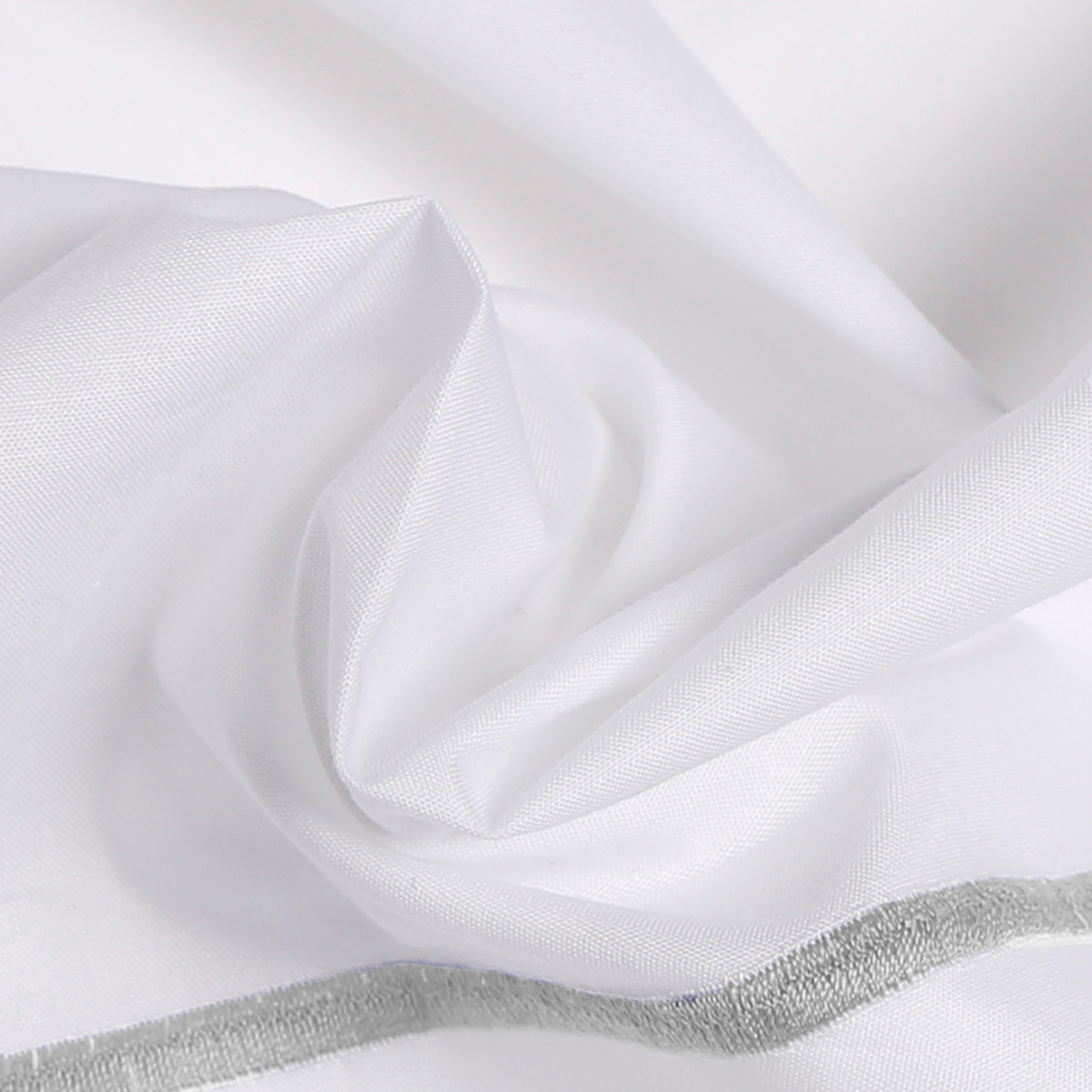 White fabric with a smooth texture is loosely gathered, like hotel bed linens, showing a visible seam and light gray stitched border.
