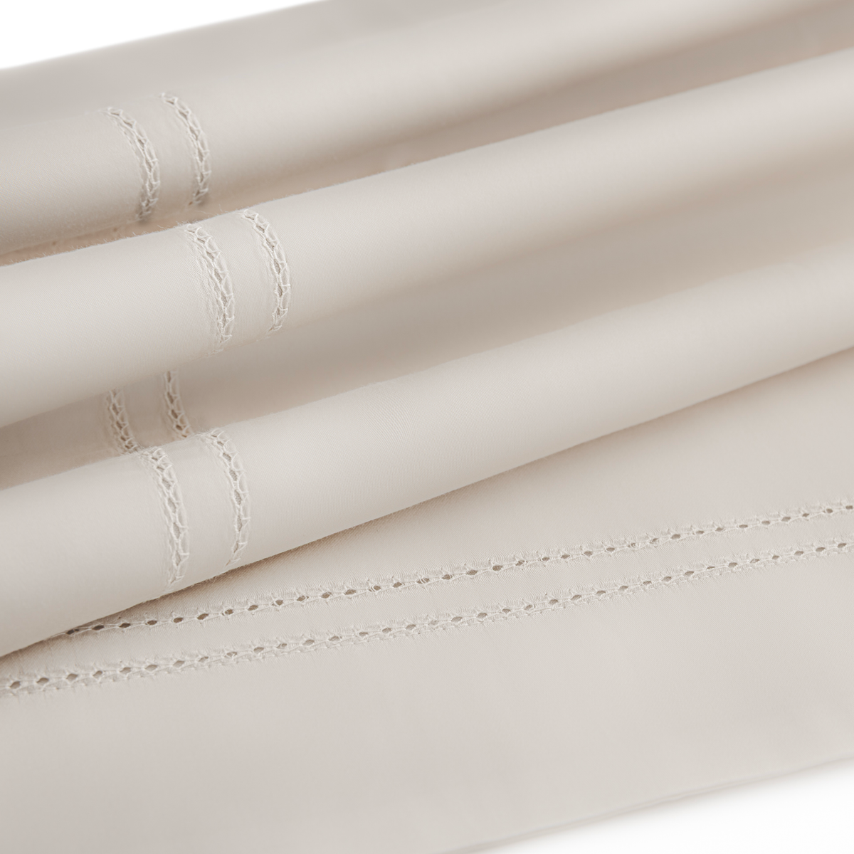 Folded luxury cotton sateen sheets with decorative stitched lines near the edges on a plain surface.