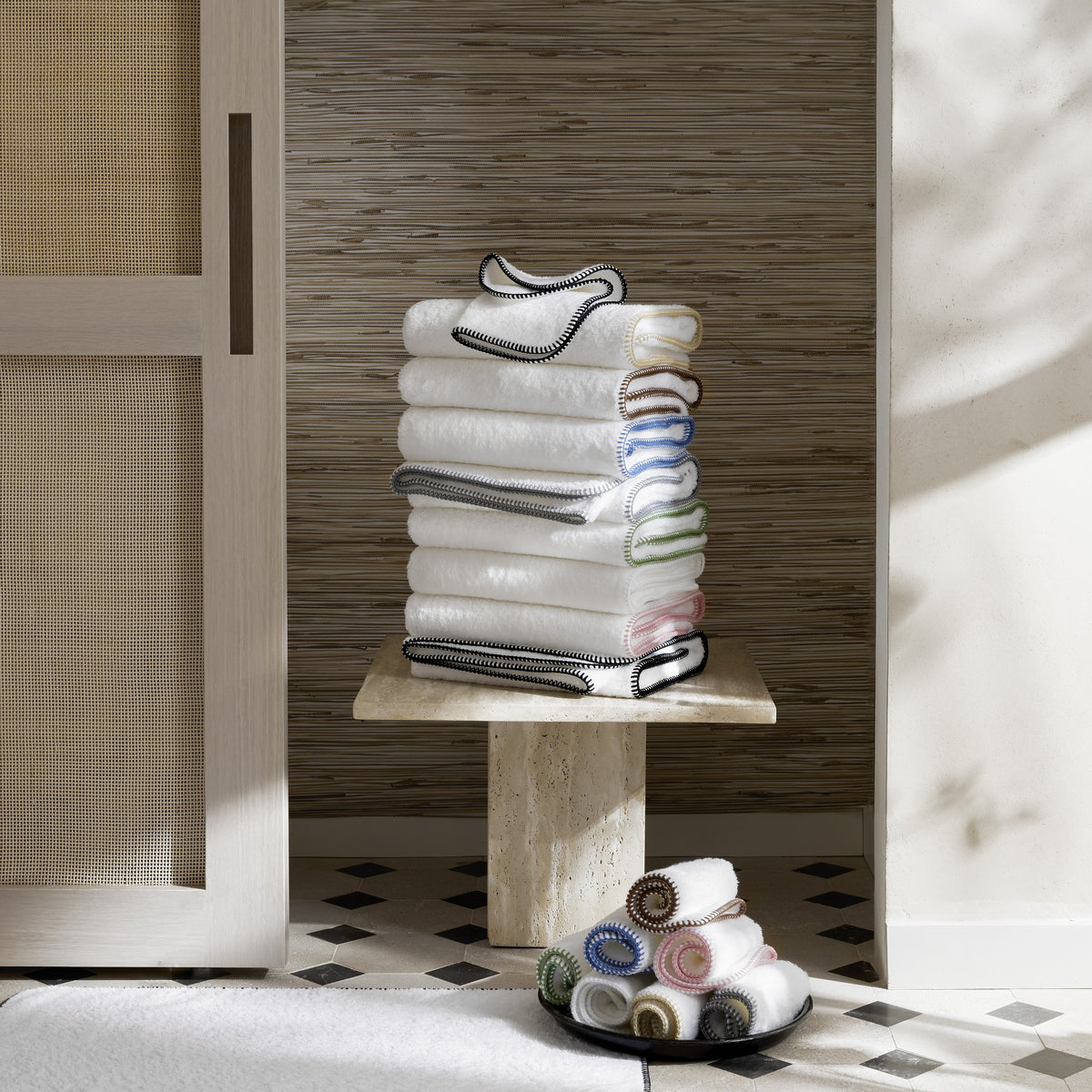 Stack of folded towels on a wooden stool against a wooden wall.