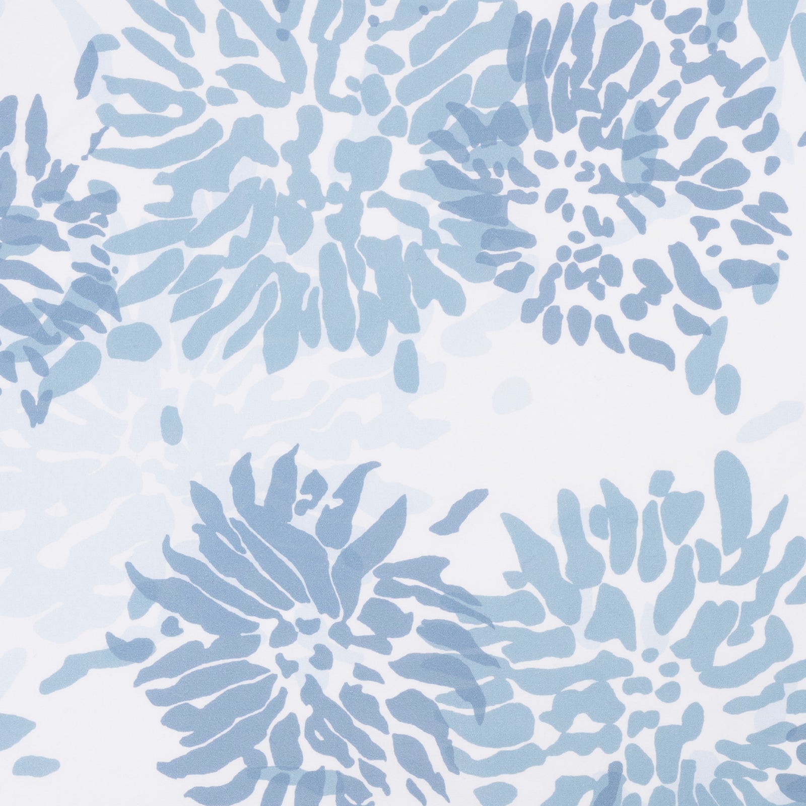 Pillows and folded Matouk Chrysanthemum luxury bedding with floral prints on wooden tables, set against a blue background