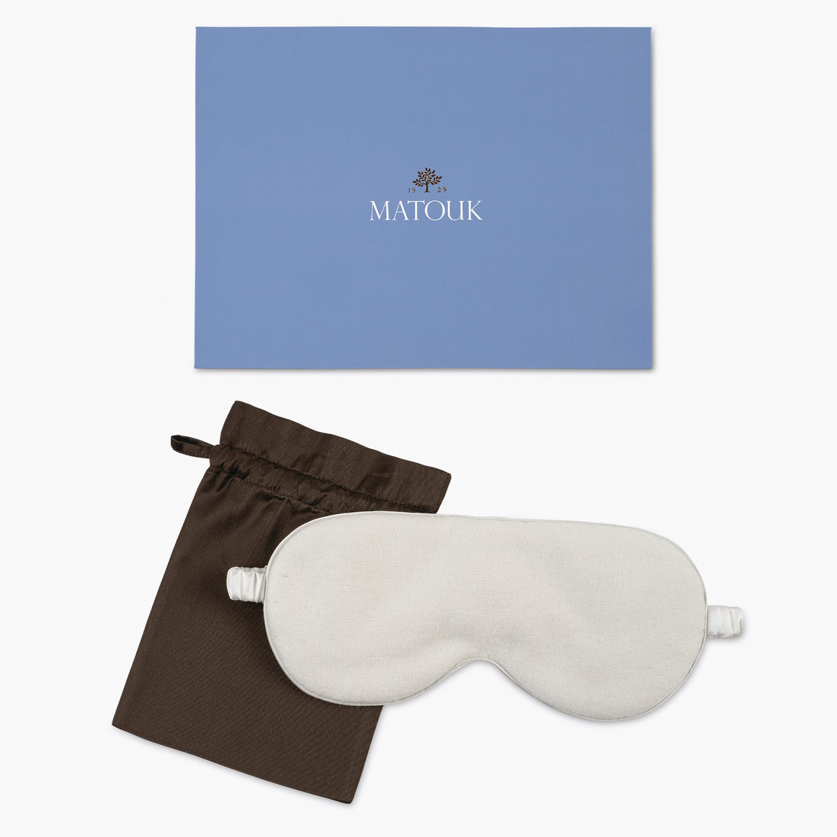 White sleep mask with brown pouch and blue Matouk branded box on a white background