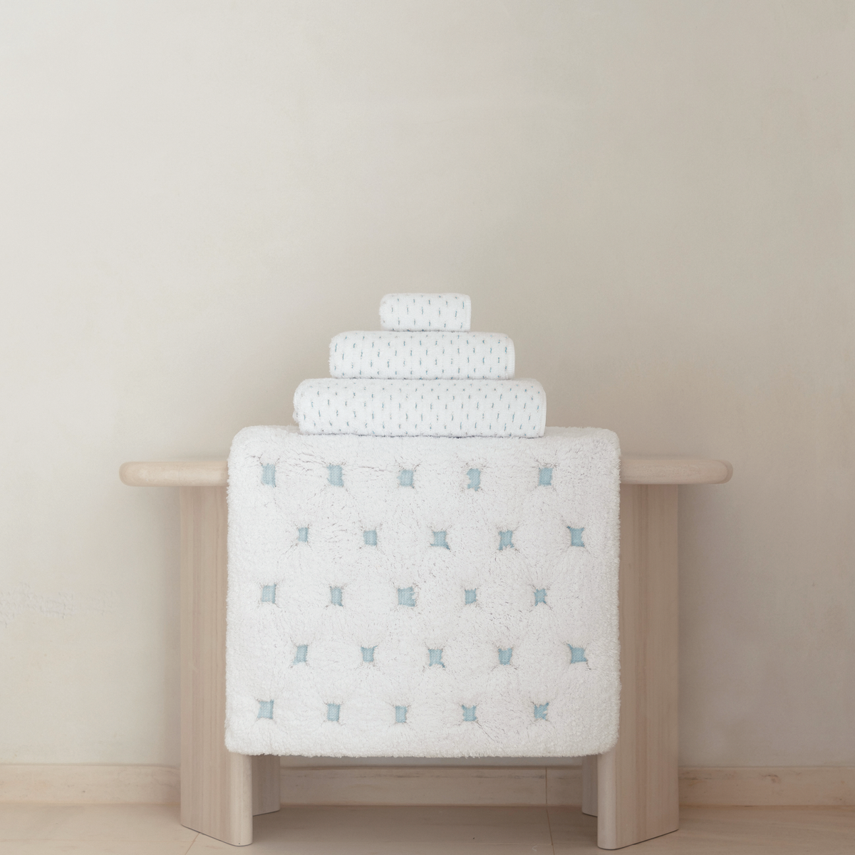 Graccioza Alice Bath Towels and Rugs in White and Sea Mist colors on wooden table
