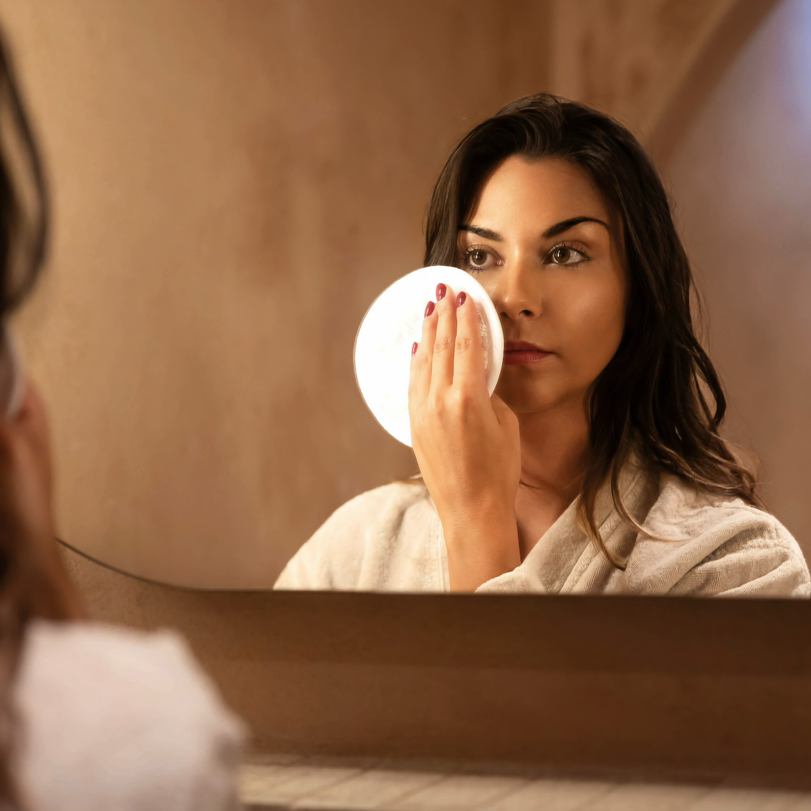 Female Looking into Mirror while using Graccioza Egoist Make Up Remover in White