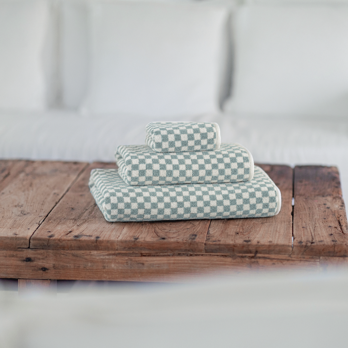 Graccioza Estoril Bath Towels and Rugs in Seamist and Snow colors on wooden table