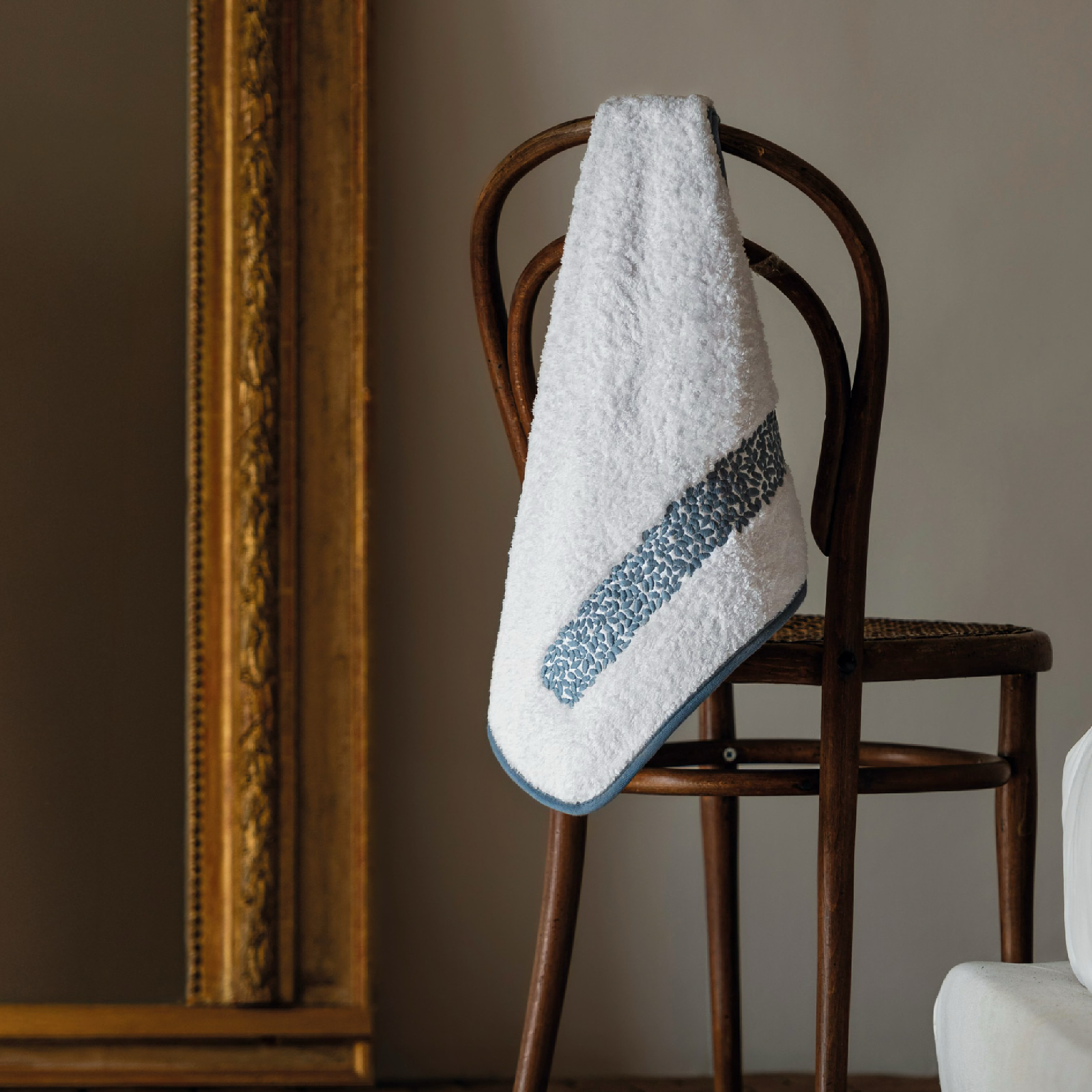 Graccioza Malone Bath Towel in White and French Blue hanging on a stool