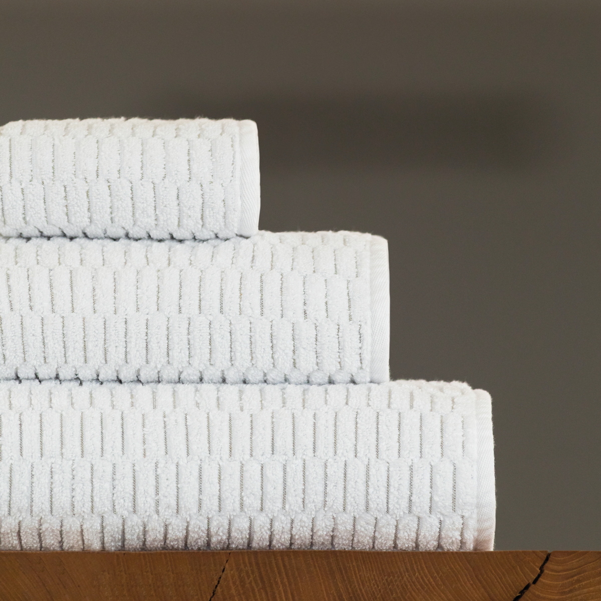 Stack of White Graccioza Riva Bath Towels on wooden surface
