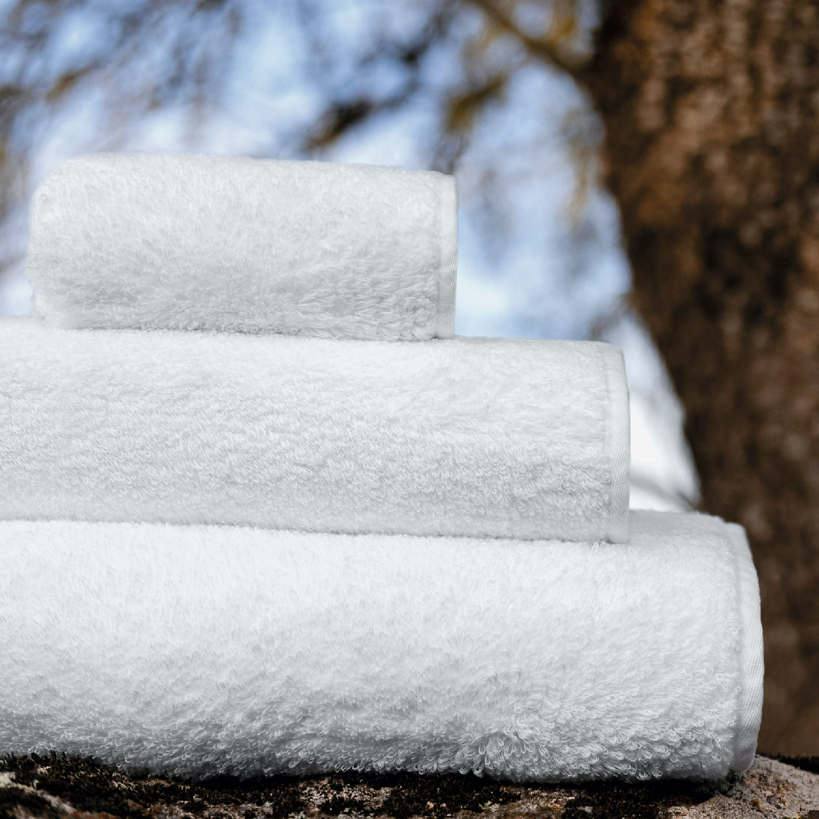 Stack of White Graccioza Tecnic Bath Towels in the woods