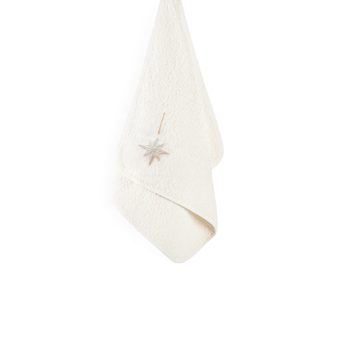 A cream-colored Graccioza Sparkle bath towel hanging with a star-shaped ornament attached.