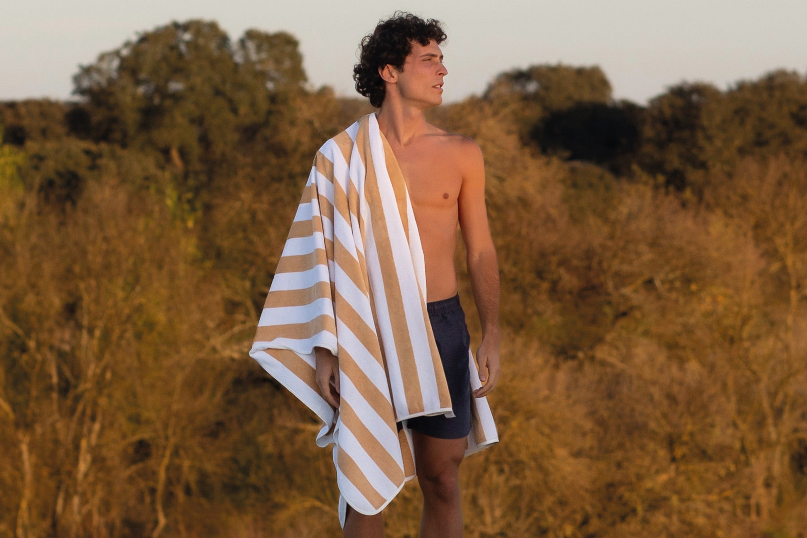 Man standing at edge of infinity pool with Aveiro Beach Towel over his shoulder