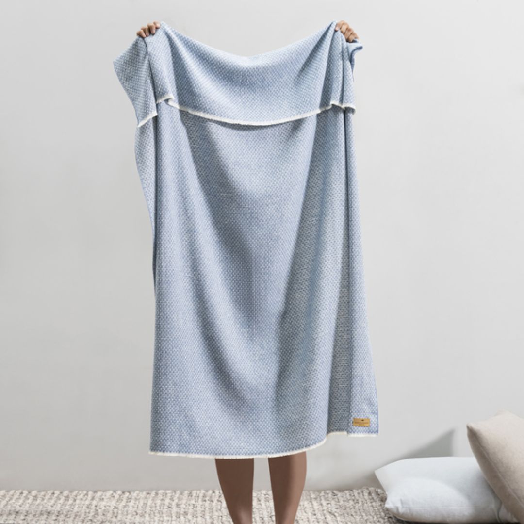 Person holding up a Lands Downunder Hudson Valley Throw in Chambray color