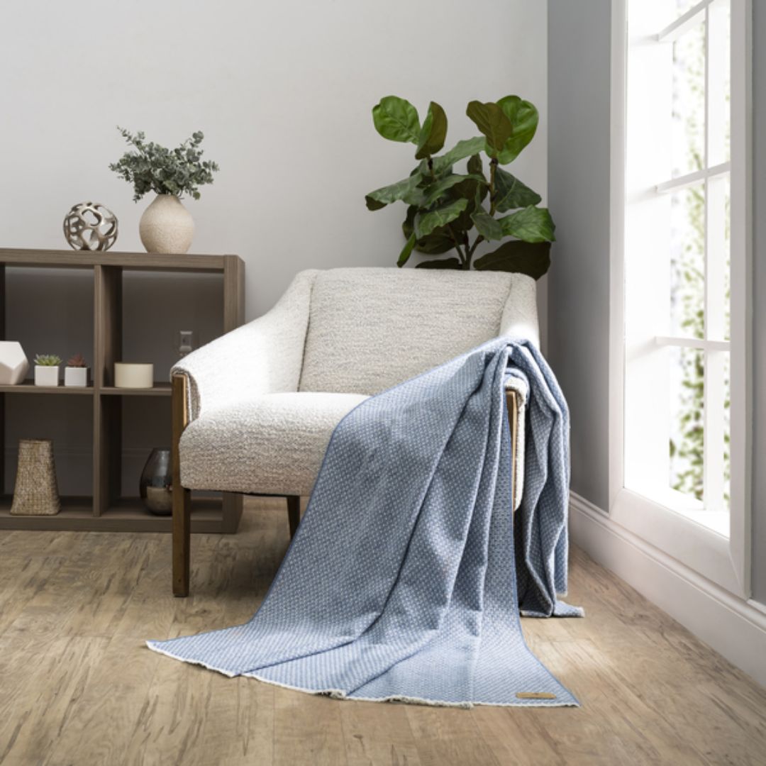 Cozy living room with a gray armchair draped with a Lands Downunder Hudson Valley Throw in Chambray color