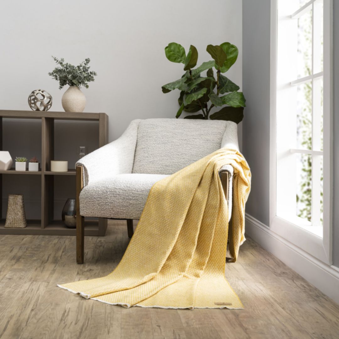 Cozy living room with a gray armchair draped with a Lands Downunder Hudson Valley Throw in Cider color