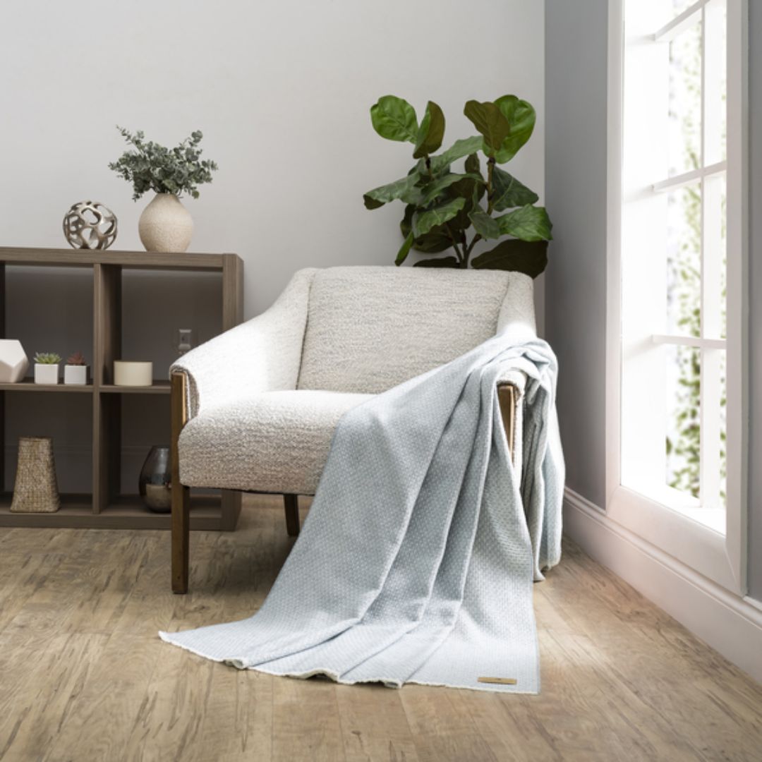 Cozy living room with a gray armchair draped with a Lands Downunder Hudson Valley Throw in Crystal Blue color