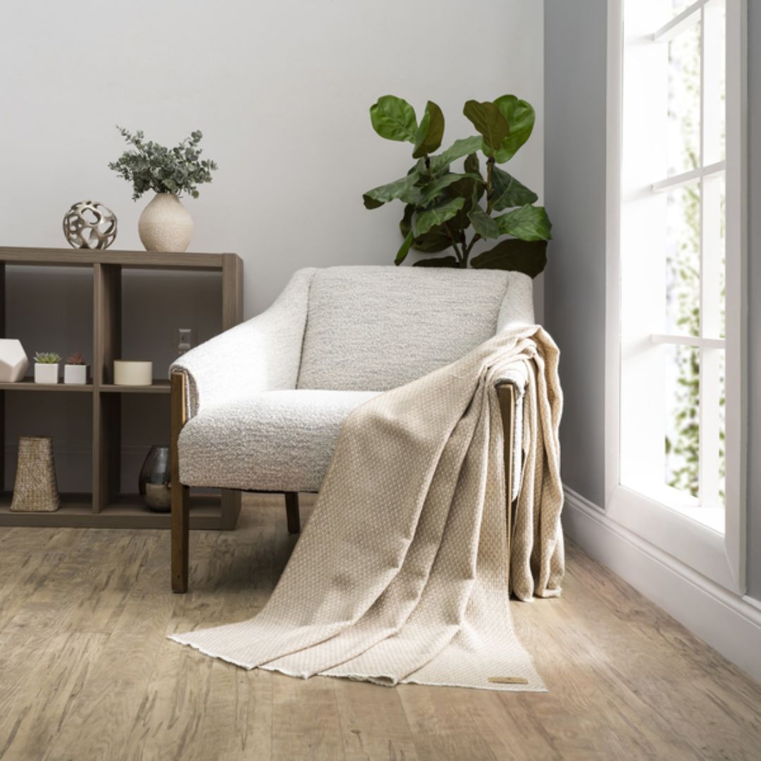 Cozy living room with a gray armchair draped with a Lands Downunder Hudson Valley Throw in Dune color
