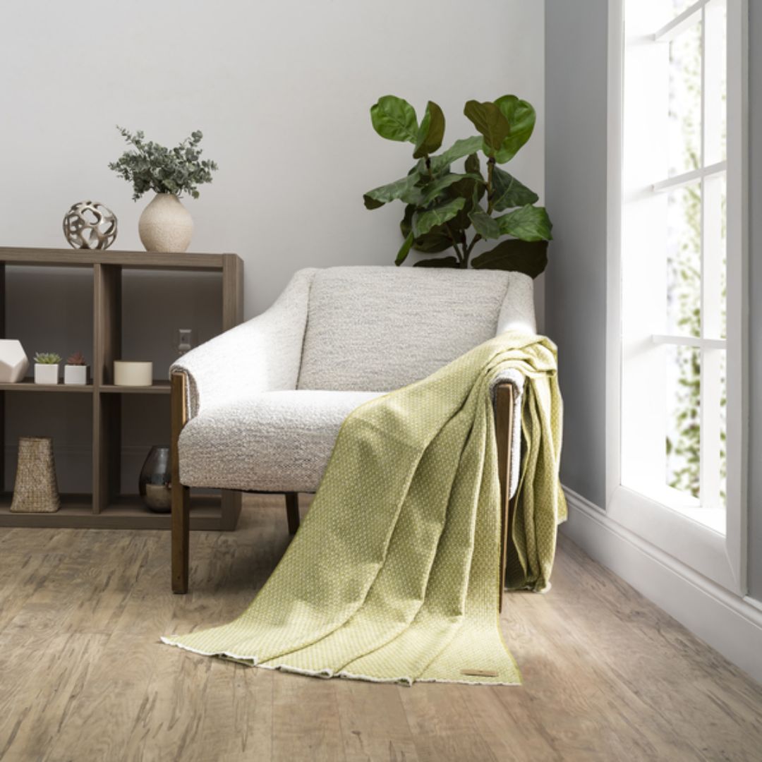 Cozy living room with a gray armchair draped with a Lands Downunder Hudson Valley Throw in Lemongrass color