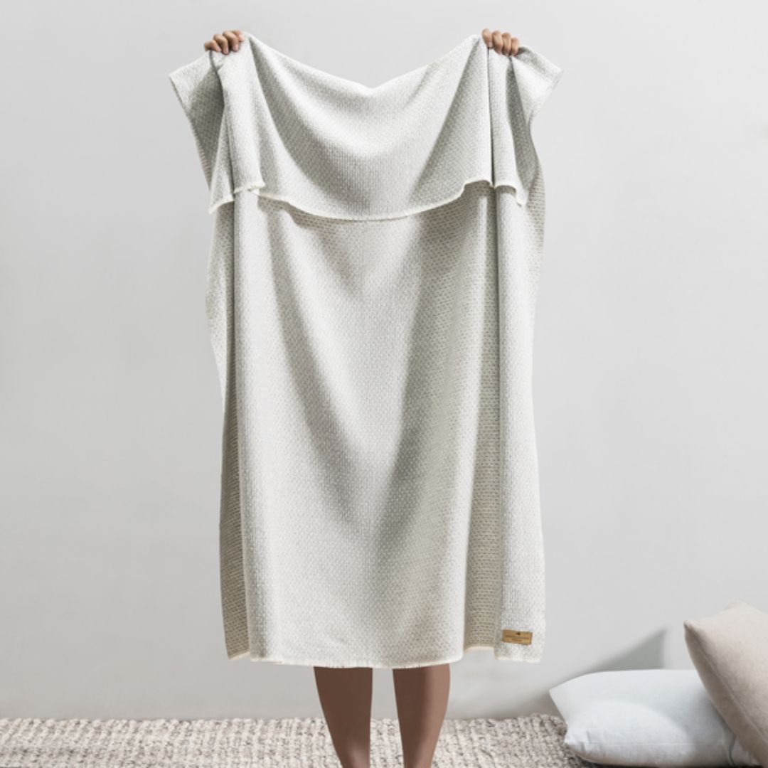 Person holding up a Lands Downunder Hudson Valley Throw in Light Gray color
