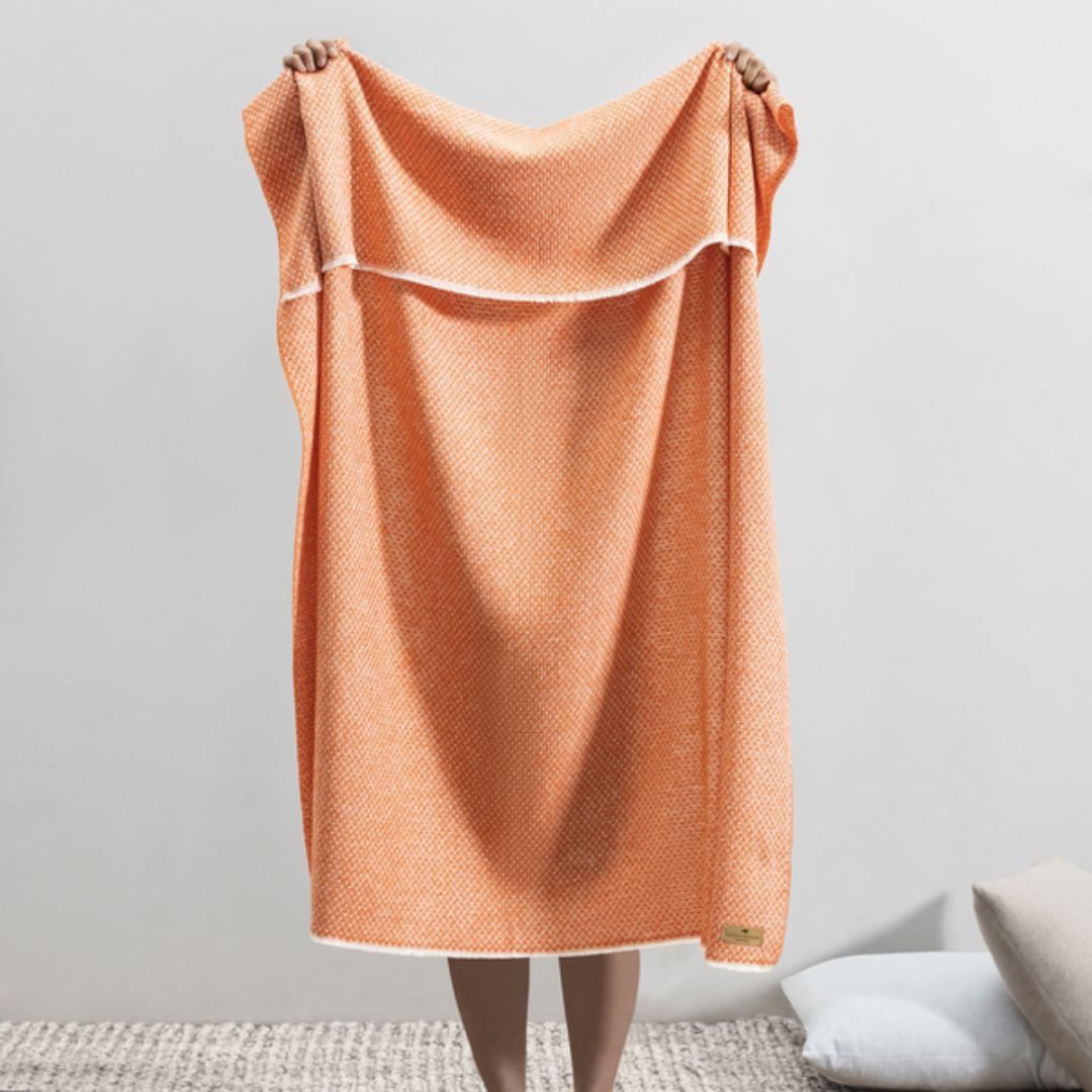 Person holding up a Lands Downunder Hudson Valley Throw in Mandarin color